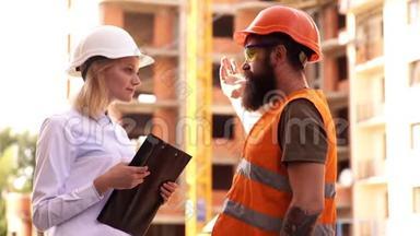 男女土木工程师在施工现场交谈。 建筑中的男女建筑工人。